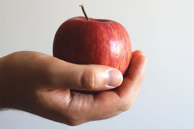 A person holding a fresh apple showing the Health Benefits of Apples