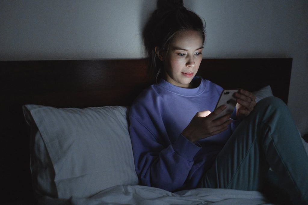 Person falling asleep with phone on — a common brain damaging sleep mistakes disrupting REM sleep