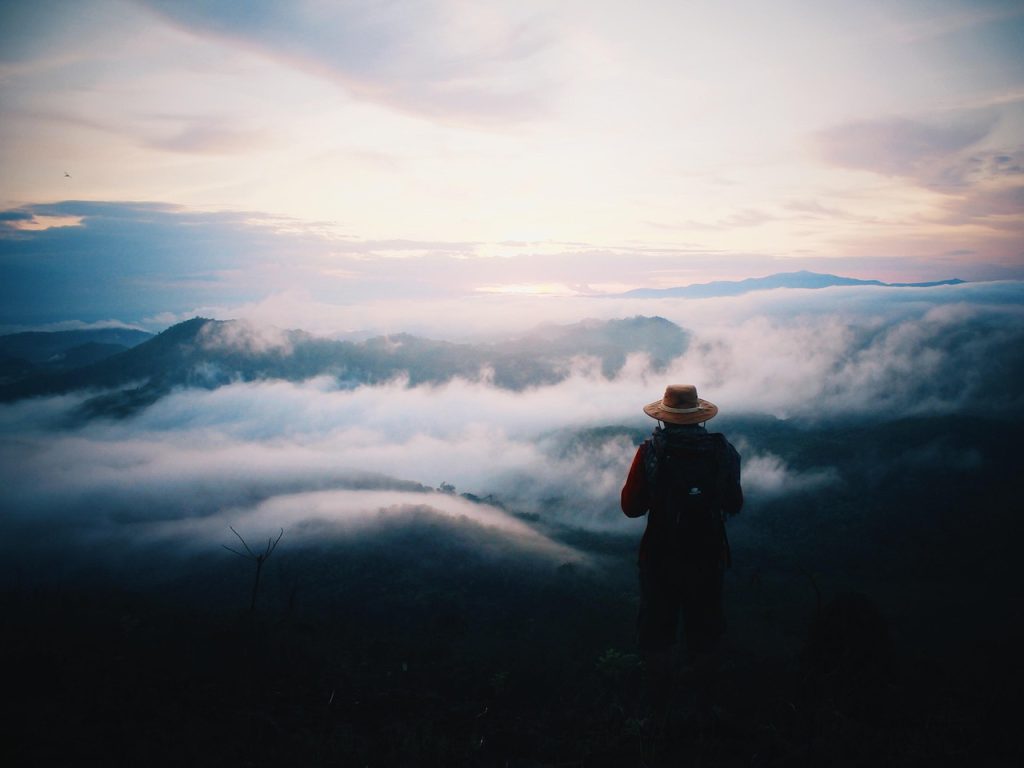 Confident person standing on a mountain at sunrise to build self-belief and inner strength