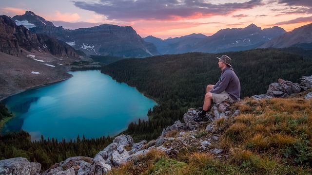 Confident person standing on a mountain peak at sunrise symbolizing the journey to build self-belief and personal growth