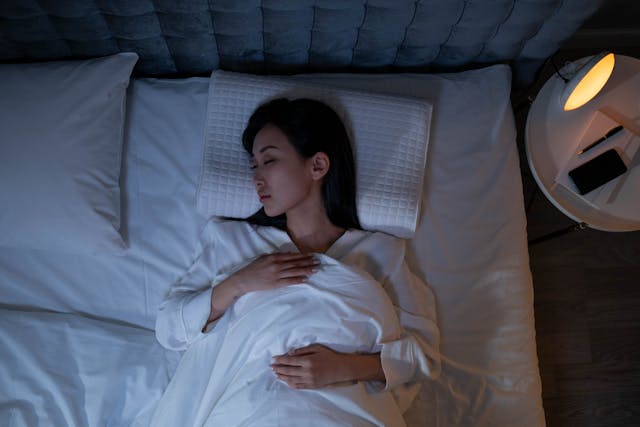 Woman enjoying deep restful sleep in cozy bedroom for better mental wellness