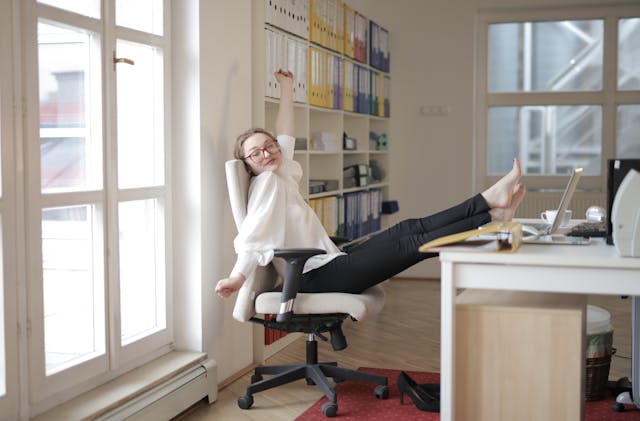 Woman practicing desk yoga stretch routine at office desk to boost productivity