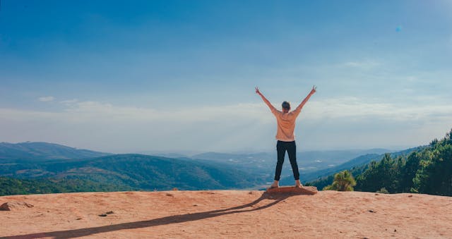 A person standing on a mountain at sunrise symbolizing growth mindset motivation and personal achievement