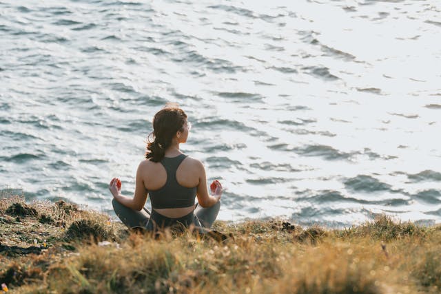 A solo traveler meditating in peaceful nature during a budget wellness retreats