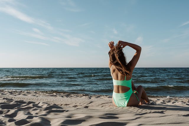 Solo women adventure traveler reflecting and enjoying sunset at the beach