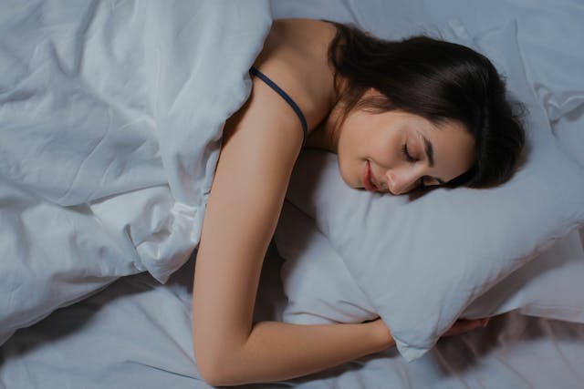 Relaxed woman in bed showing deep sleep benefits for stress relief