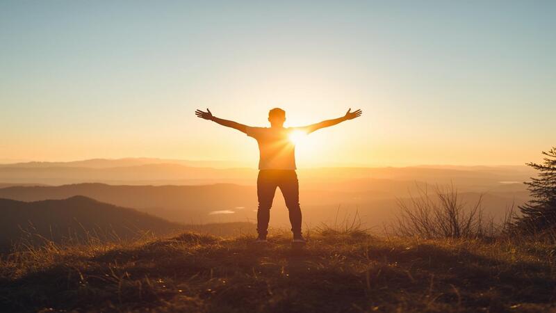 Empowered person on a hilltop with sunrise, representing self-growth and motivation to Stop Comparing Yourself.